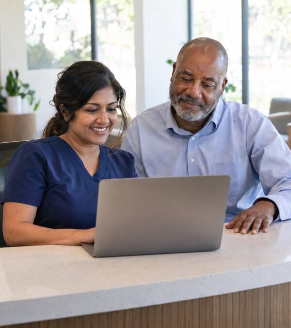A dental practice team reviews its marketing results on a laptop at the front desk